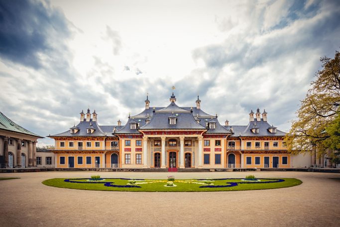 Historisches Schloß Pillnitz mit bunten Fassaden und einem weitläufigen Garten. 
