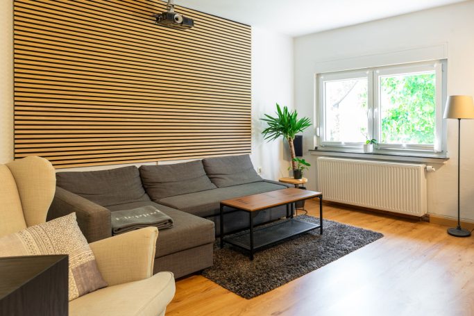 Helle Wohnzimmer-Einrichtung mit Sofa, Tisch, Pflanze und Fenster.