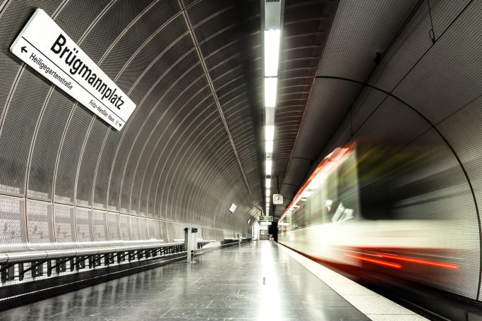 U-Bahn-Station mit verschwommener Bahn und modernen, grauen Wänden.